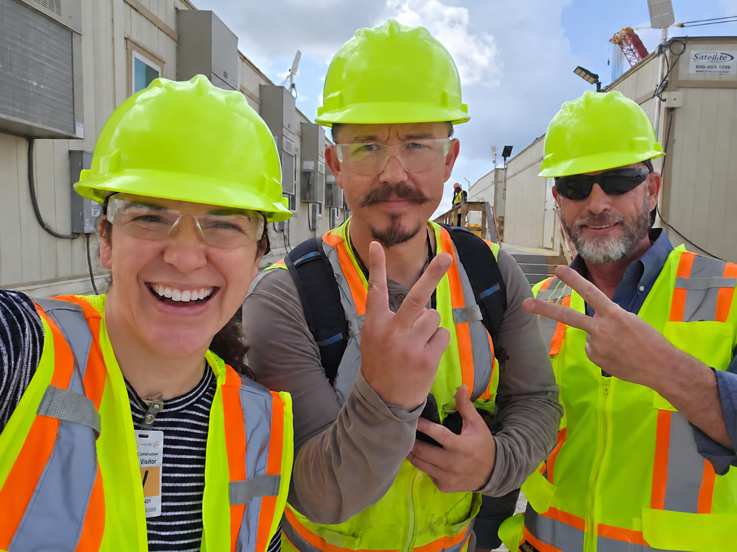 Two Multiplied team members and a customer on a site visit, wearing safety vests and hardhats.